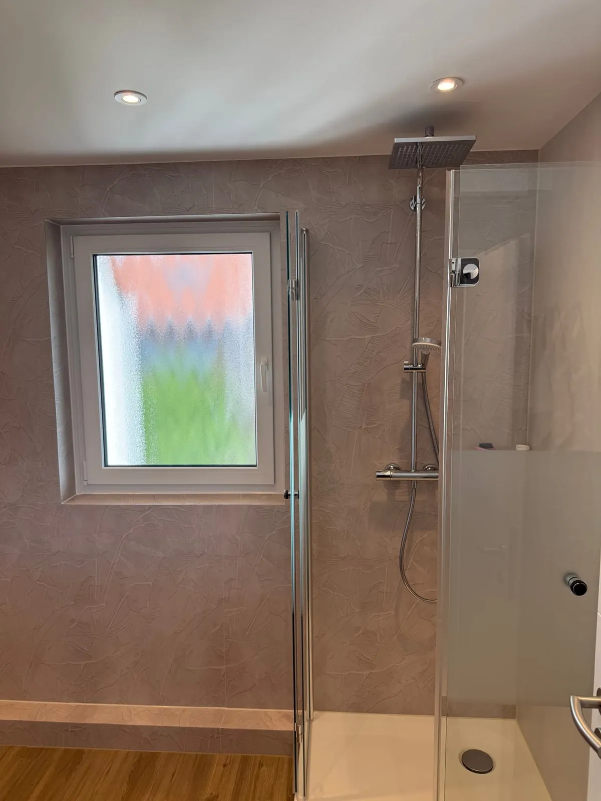 Fugenlose Dusche mit Glasabtrennung neben dem Fenster