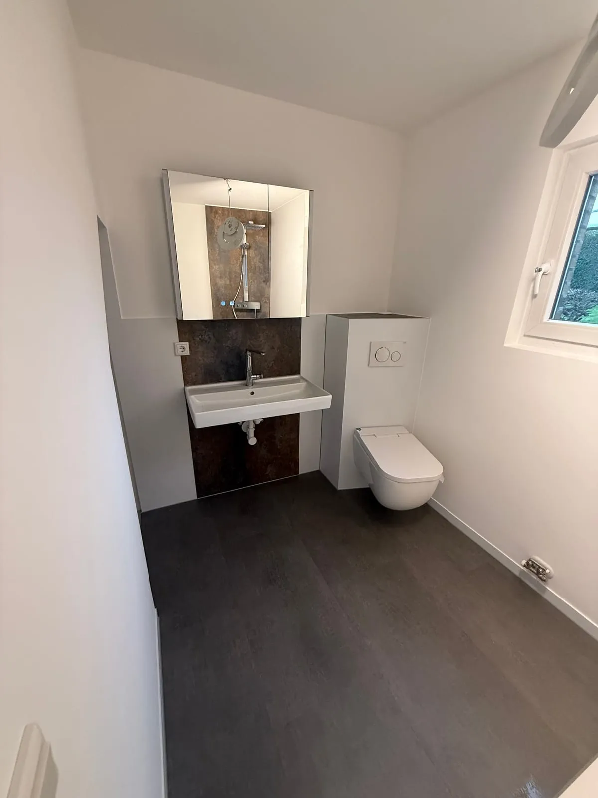 Fugenloses Gäste-WC mit Waschtisch und Bronze-Wand